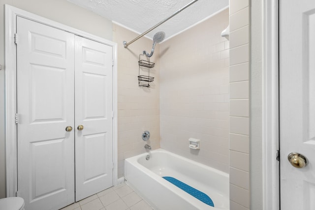 bathroom with tiled shower / bath, a textured ceiling, toilet, and tile patterned floors