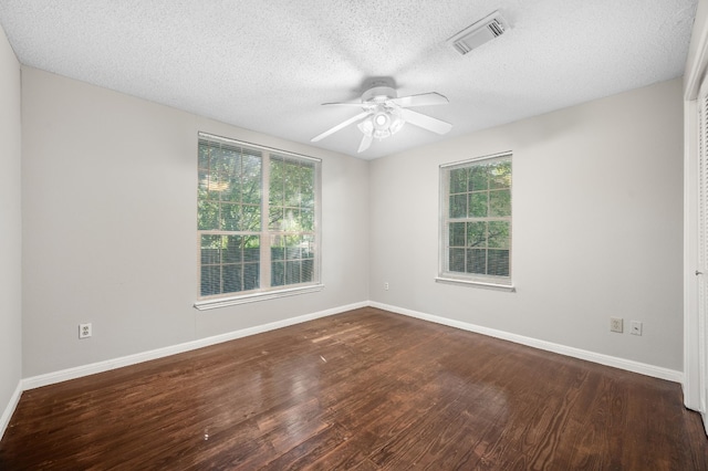 spare room with dark wood-type flooring, a healthy amount of sunlight, and ceiling fan