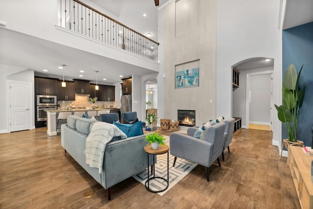 living room featuring hardwood / wood-style floors, a towering ceiling, and a fireplace