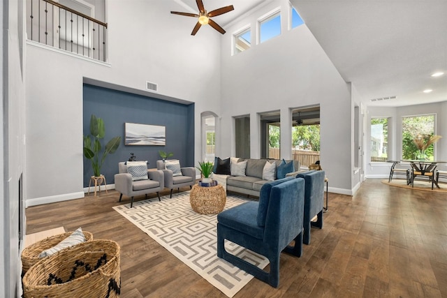 living room featuring ceiling fan, wood-type flooring, and a towering ceiling