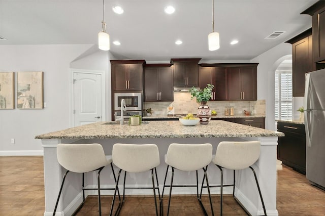 kitchen featuring decorative light fixtures, sink, an island with sink, and appliances with stainless steel finishes