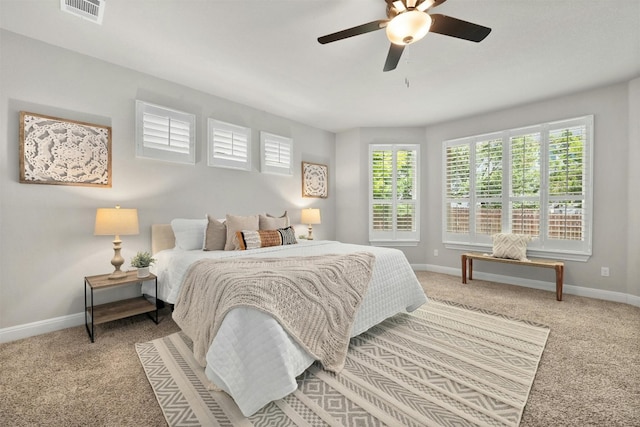 carpeted bedroom featuring multiple windows and ceiling fan