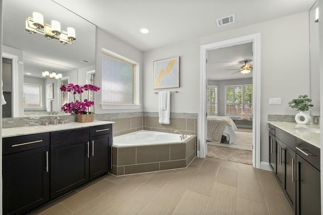 bathroom featuring tile patterned floors, ceiling fan, tiled tub, and vanity