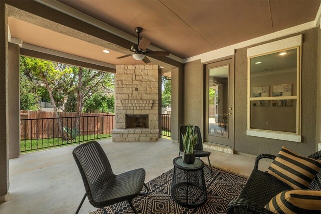 view of patio with an outdoor stone fireplace and ceiling fan