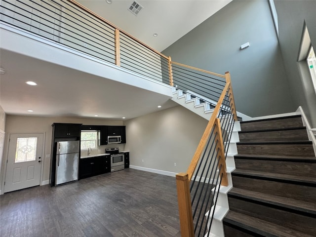 staircase featuring sink, dark hardwood / wood-style floors, and a towering ceiling