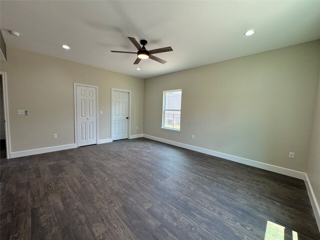 unfurnished bedroom featuring multiple closets, ceiling fan, and dark hardwood / wood-style floors