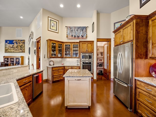 kitchen with appliances with stainless steel finishes, brown cabinets, visible vents, and a kitchen island