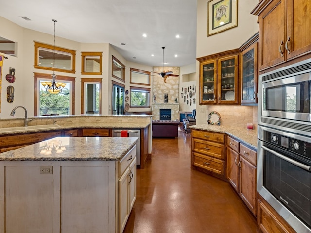 kitchen featuring stainless steel appliances, a wealth of natural light, a sink, and a stone fireplace