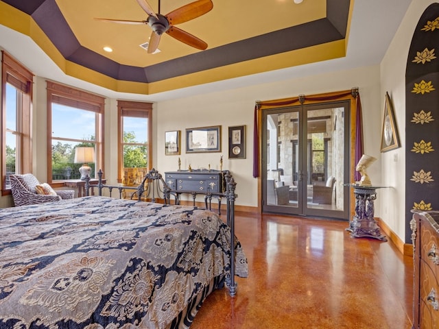 bedroom featuring access to exterior, a tray ceiling, and baseboards