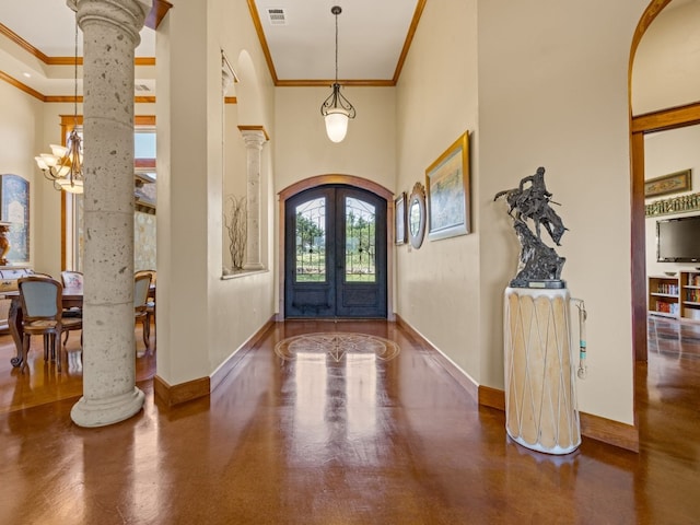 foyer entrance featuring arched walkways, french doors, a towering ceiling, and decorative columns