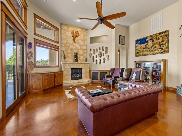 living room featuring arched walkways, visible vents, a towering ceiling, a large fireplace, and ceiling fan