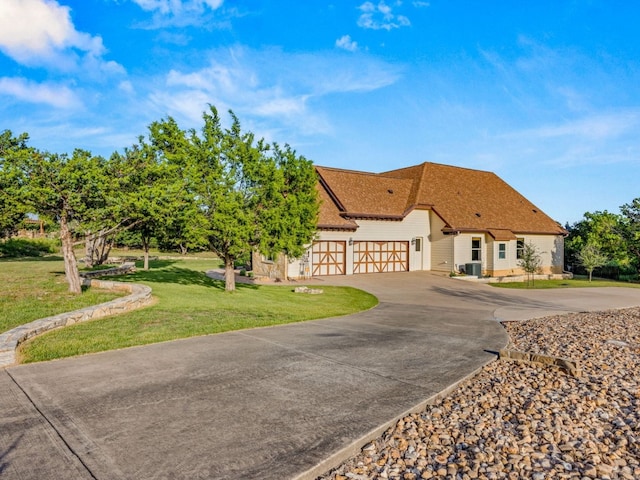 view of front of house with a front yard, roof with shingles, driveway, and an attached garage