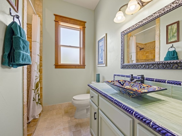 full bath with vanity, a tile shower, and toilet