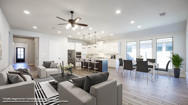 living room featuring light hardwood / wood-style floors, sink, a wealth of natural light, and ceiling fan