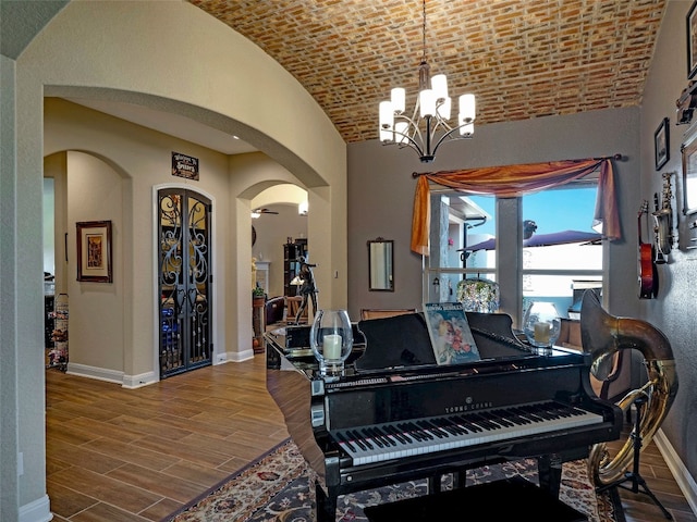 miscellaneous room featuring hardwood / wood-style floors, vaulted ceiling, a chandelier, and brick ceiling