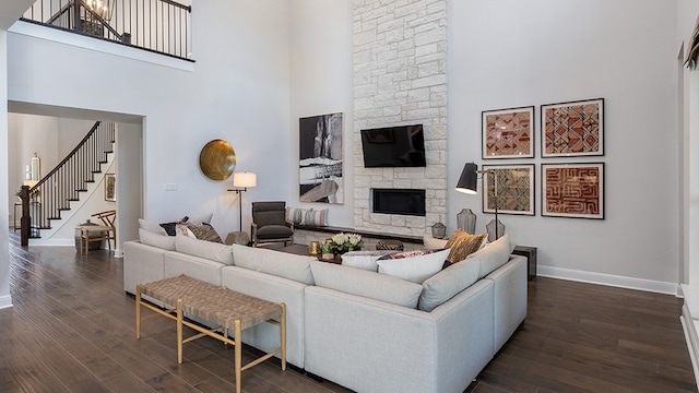 living room featuring a fireplace, dark wood-type flooring, and a high ceiling