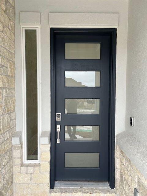 doorway to property with stone siding and stucco siding