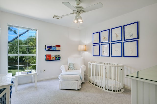 carpeted bedroom featuring a crib and ceiling fan