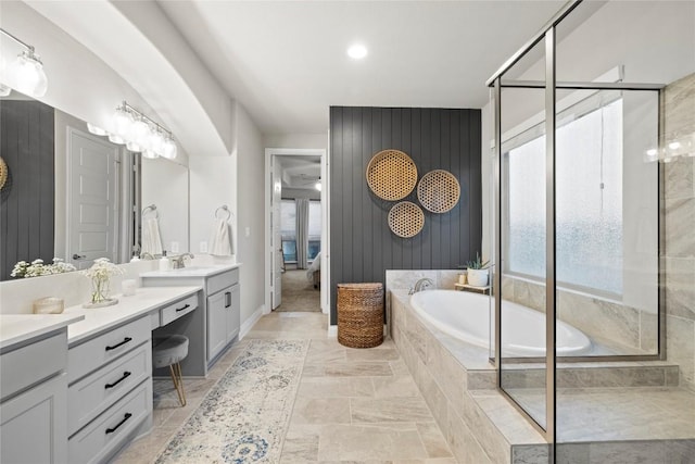 bathroom featuring a relaxing tiled tub, vanity, and wooden walls