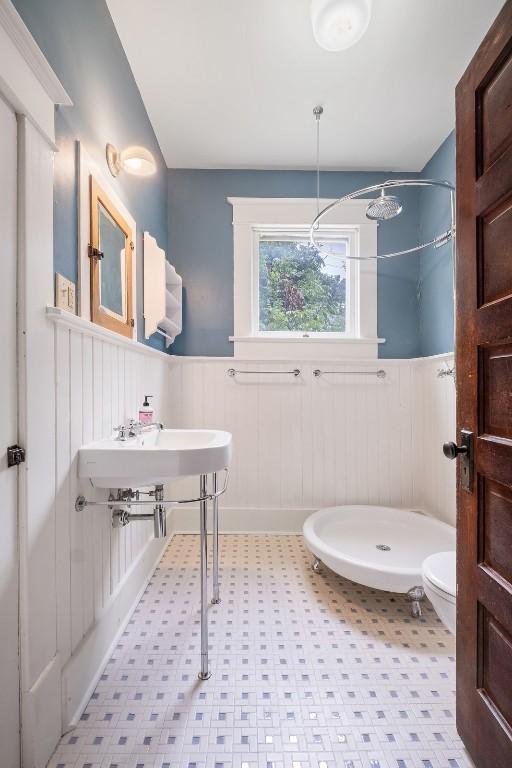 bathroom featuring toilet, a wainscoted wall, a shower stall, and tile patterned floors