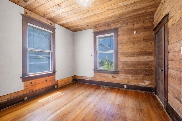 spare room featuring wooden walls, wood ceiling, and wood-type flooring