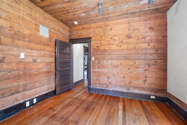 unfurnished room with wooden ceiling, hardwood / wood-style flooring, and wooden walls