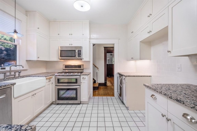 kitchen with stainless steel appliances, light stone counters, a sink, and white cabinets