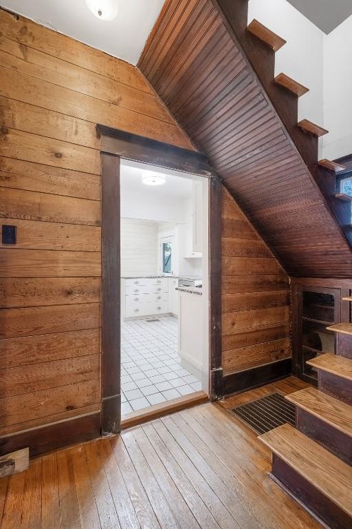 bonus room featuring hardwood / wood-style flooring, wooden walls, stairway, and vaulted ceiling