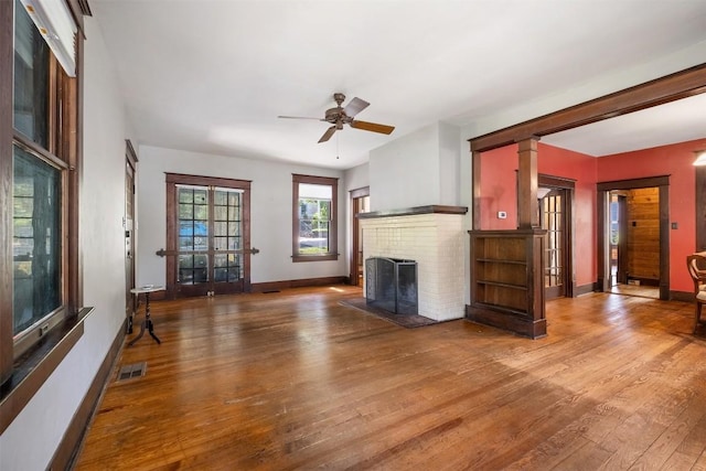 unfurnished living room with a fireplace, visible vents, ceiling fan, baseboards, and hardwood / wood-style flooring