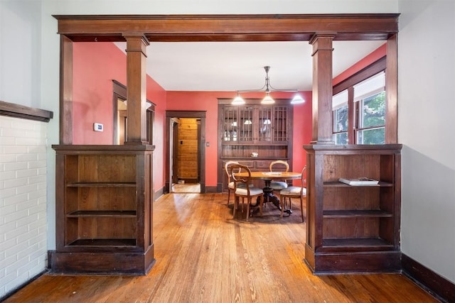 bar with baseboards, hardwood / wood-style flooring, and ornate columns