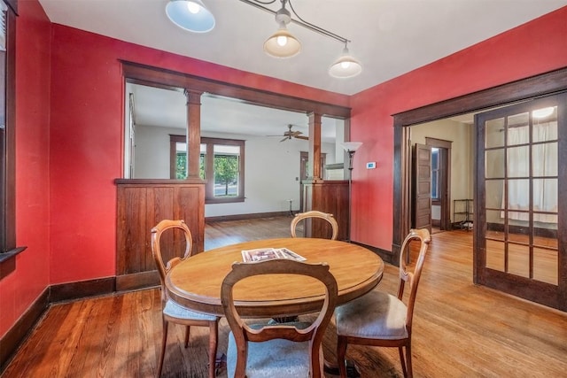 dining area featuring baseboards, wood finished floors, and ornate columns