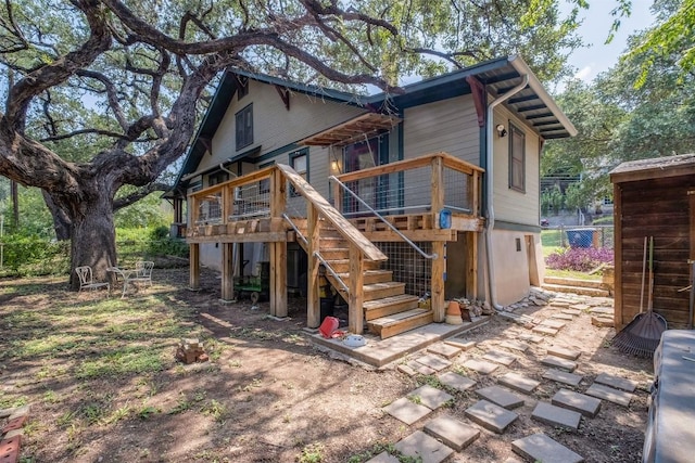 back of house featuring stairs and a wooden deck