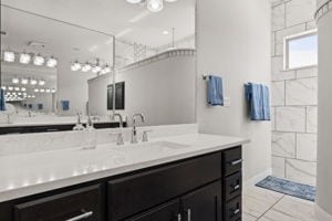 bathroom with tiled shower and vanity