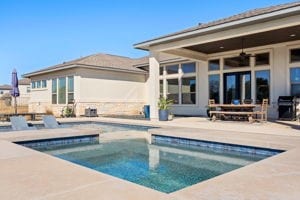 back of property featuring ceiling fan, a pool with hot tub, and a patio