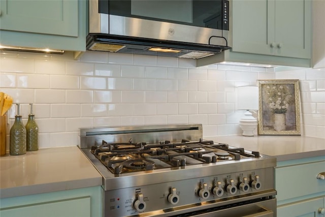 kitchen featuring backsplash, green cabinets, and stainless steel appliances