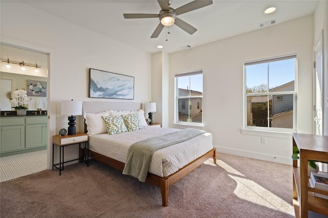 bedroom featuring ensuite bath, dark carpet, and ceiling fan