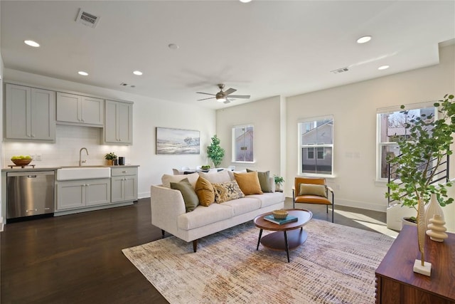 living room with dark hardwood / wood-style floors, ceiling fan, and sink