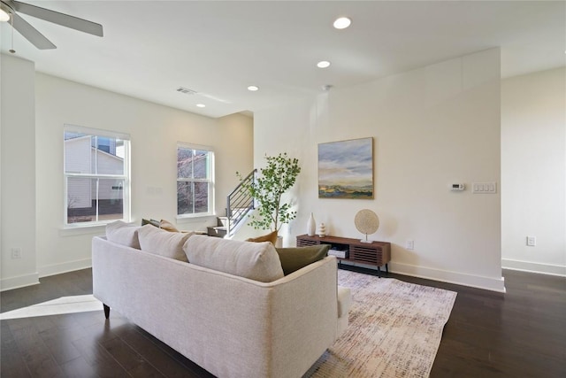 living room featuring ceiling fan and dark wood-type flooring