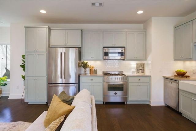 kitchen with dark hardwood / wood-style flooring, stainless steel appliances, and tasteful backsplash