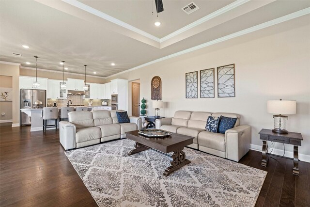 living room featuring crown molding, dark hardwood / wood-style floors, and a tray ceiling