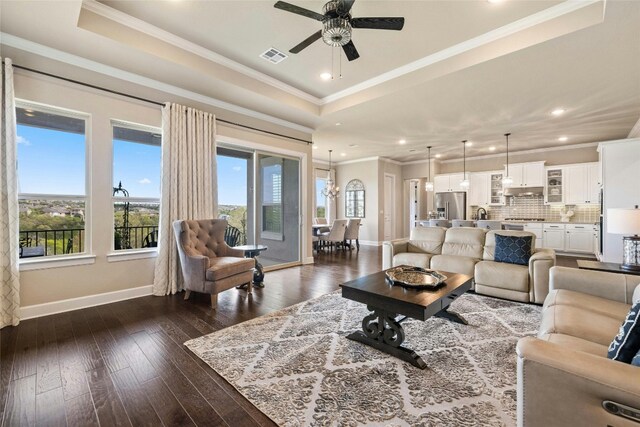 living room with a tray ceiling, visible vents, and plenty of natural light