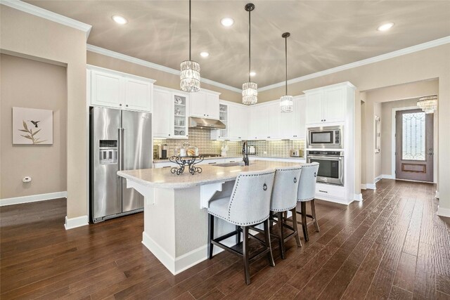 kitchen with tasteful backsplash, stainless steel appliances, dark hardwood / wood-style flooring, white cabinets, and ornamental molding