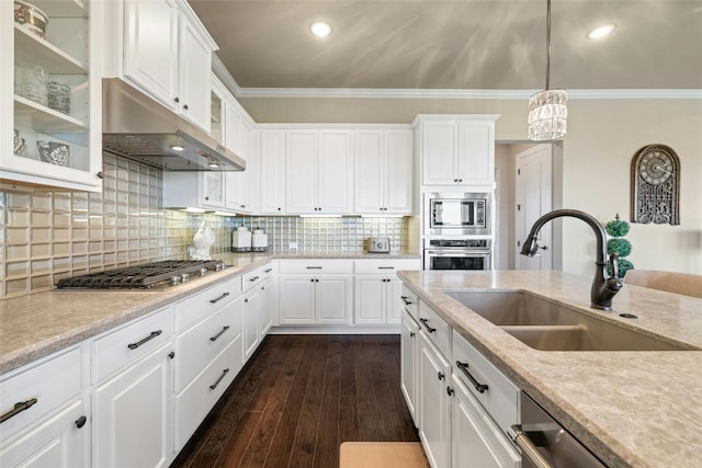 kitchen featuring dark wood finished floors, glass insert cabinets, ornamental molding, stainless steel appliances, and a sink