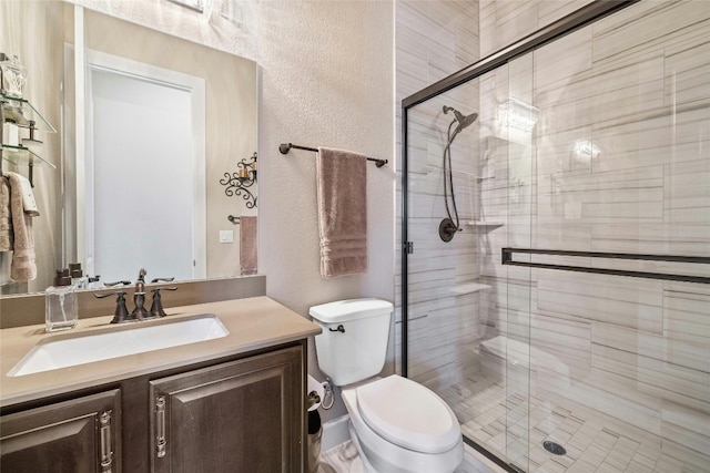 full bath featuring a textured wall, vanity, a shower stall, and toilet