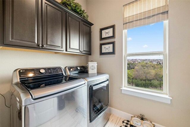 laundry room with cabinets, light hardwood / wood-style flooring, and washing machine and clothes dryer