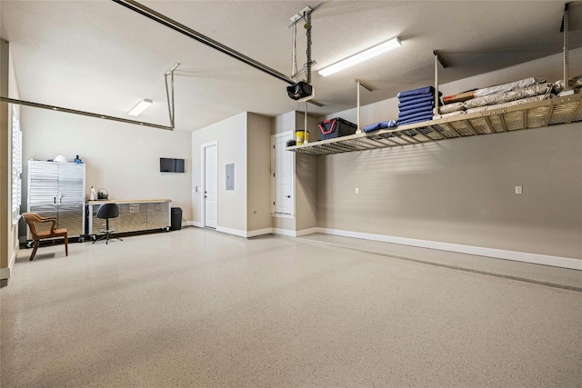 garage featuring a garage door opener, electric panel, and baseboards