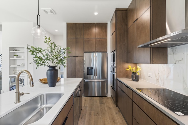 kitchen featuring decorative light fixtures, sink, dark hardwood / wood-style flooring, stainless steel appliances, and wall chimney exhaust hood