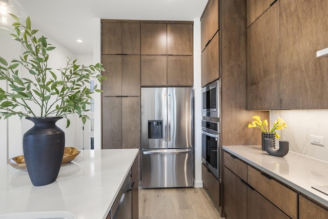 kitchen with light hardwood / wood-style flooring, stainless steel appliances, and tasteful backsplash