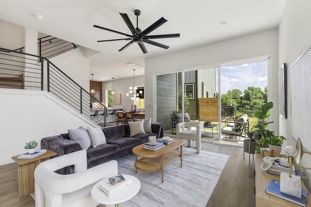 living room featuring ceiling fan with notable chandelier and light hardwood / wood-style flooring