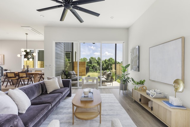 living room with ceiling fan with notable chandelier and hardwood / wood-style flooring